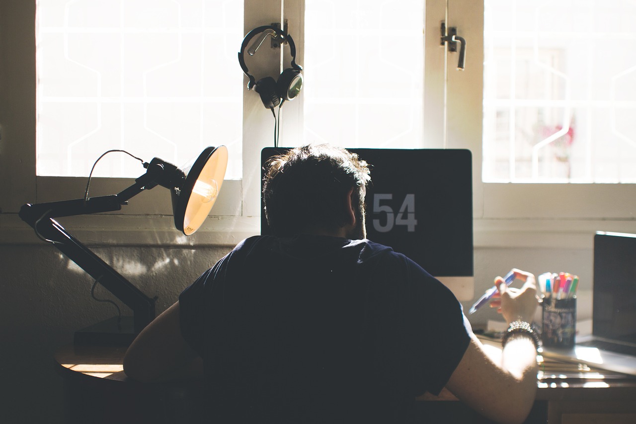 man focusing at his desk in front of a A man focusing at his desk in front of a window