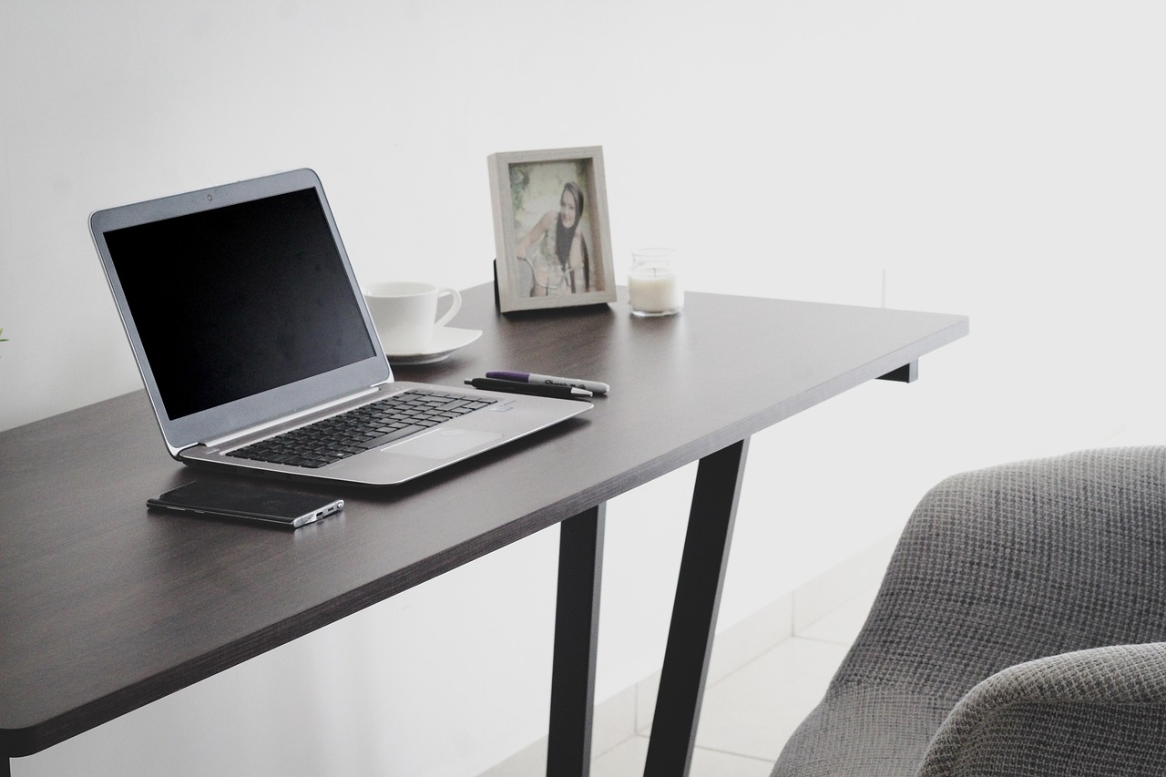 desk workspace with a picture and a laptop A desk workspace with a framed picture and a laptop
